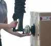 Eine Frau bewegt mithilfe des Vakuum-Schlauchhebers einen Karton.